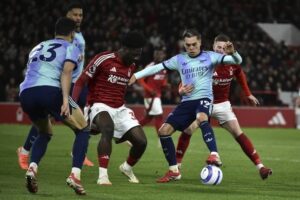 Ola Aina berebut bola dengan Leandro Trossard dalam laga Premier League 2024/2025 antara Nottingham Forest vs Arsenal di City Ground, Kamis (27/2/2025) dini hari WIB. (c) AP Photo/Rui Viera
