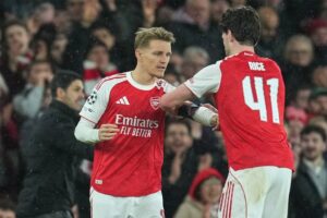 Pemain Arsenal, Martin Odegaard, menerima ban kapten dari Declan Rice saat ia masuk ke lapangan pada laga fase liga Liga Champions antara Arsenal vs Bayern Munchen, 26 November 2025 (c) AP Photo/Kin Cheung