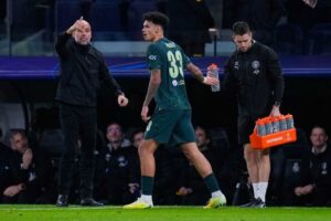 Pemain Manchester City Nico O?Reilly berdiri di samping pelatih Pep Guardiola dalam laga Liga Champions melawan Real Madrid, Rabu (10/12/2025). (c) AP Photo/Manu Fernandez
