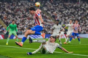 Julian Alvarez menghindari tekel Fede Valverde di laga Atletico Madrid vs Real Madrid, Jumat (09/01/2026). (c) AP Photo/Altaf Qadri