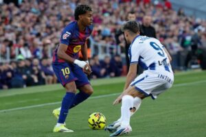 Pemain Levante, Ivan Romero, menjaga pergerakan pemain Barcelona, Lamine Yamal, dalam pertandingan La Liga, Minggu (22/2/2026) malam WIB. (c) AP Photo/Joan Monfort